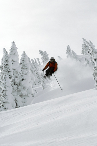 A male skier hops out of the power over a wind lip.
