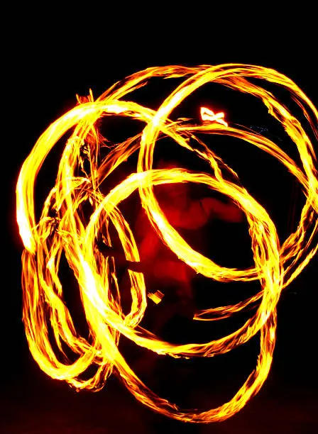 a pretty girl spins lit poi in a fire dance