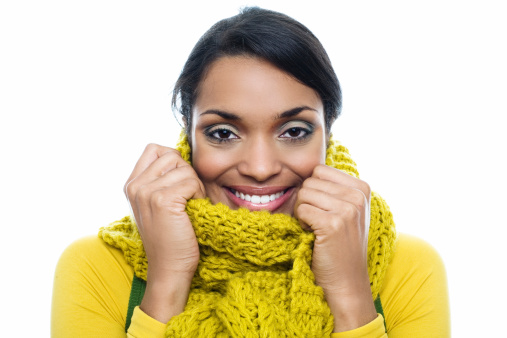 A portrait of a beautiful smiling lady bundled up in a yellow scarf.