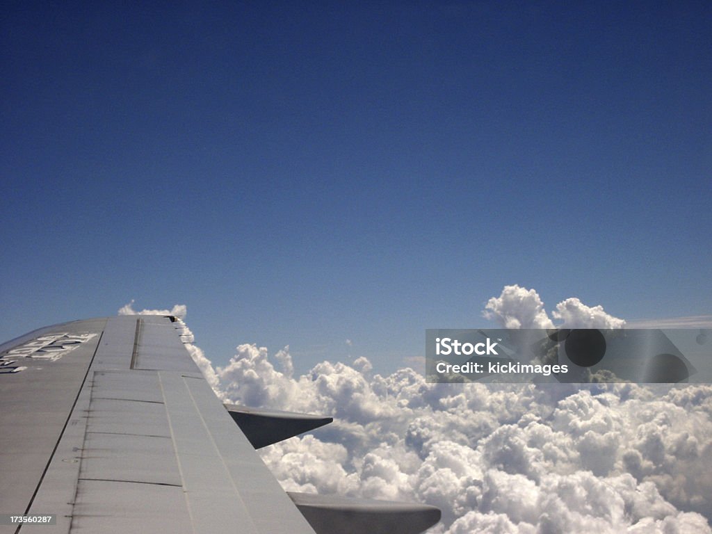 Flying Over Clouds "Looking out from an airplane, flying over clouds and blue sky." Aircraft Wing Stock Photo