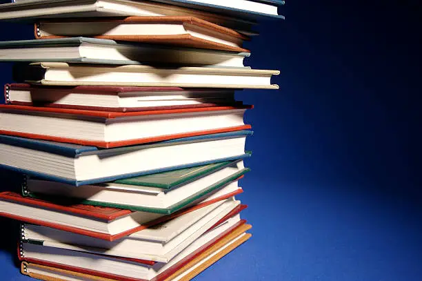 Books stacked on a blue background with spot lighting techniques