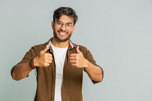 Like. Indian man raises thumbs up agrees with something or gives positive reply recommends advertisement likes good idea feedback, celebrating success victory. Guy isolated on studio gray background