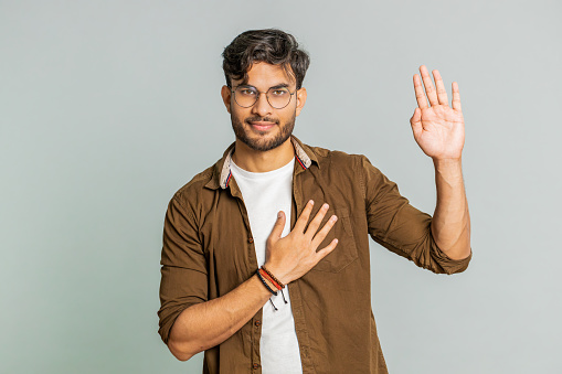 Man points with his thumb to side. Young Caucasian smiling guy with beard over isolated background pointing to side to present product. Portrait of glad cheerful man demonstrating ad copy space