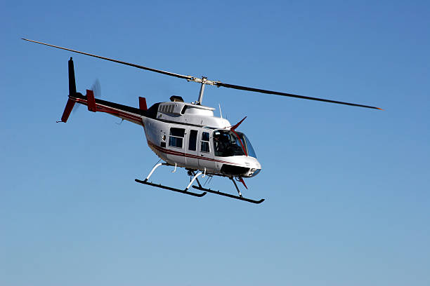 Blue and White corporate sikorsky helicopter taking off with buildings in the background.