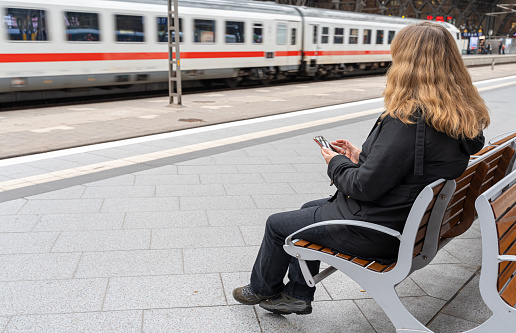 Germany, Leipzig, October 09, 2023 - Rear of woman sitting on bench at railroad station