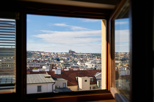 View through the open window of a hotel room over the old town of Prague with Prague Castle