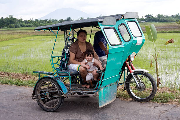 Motorcycle taxi Taxi in the Philippines. Although strictly this is a motorbike and elaborate sidecar, these are known throughout the country as 'tricycles'. Location is Bula, province of Camarines Sur, region of Bicol, island of Luzon, Phillipines. philippines tricycle stock pictures, royalty-free photos & images