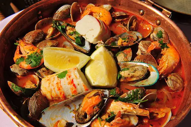 "Portuguese fish stew, known locally as a Seafood Cataplana, always cooked and served in a round copper dish. It's similar to a paella, except the rice is served separately.Image taken in a seafront restaurant in Albufeira, Algarve, Portugal."