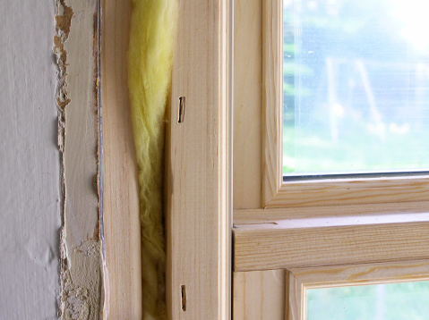 A new window is put into an old house. A swing set can be made out in the background and layers of paint are visible inside the house.