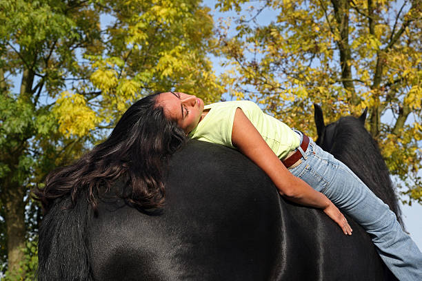 Beautiful girl resting on the back of her Friesian horse