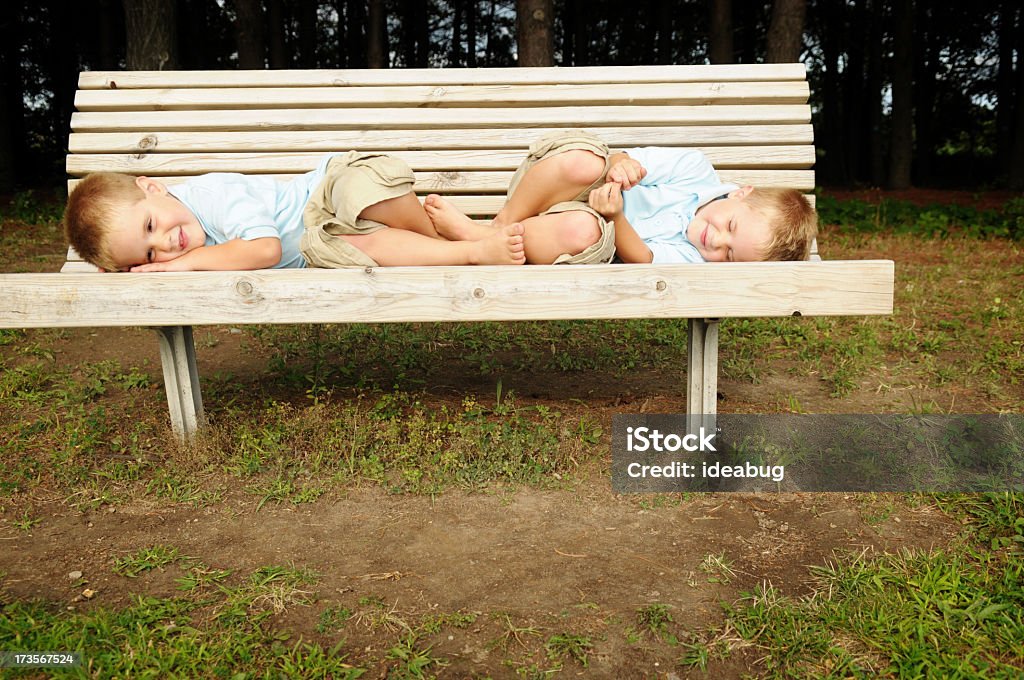 ツイン男の子に横たわる、外部ベンチ - 2人のロイヤリティフリーストックフォト