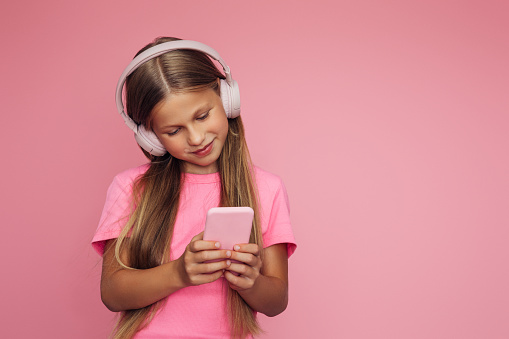 Cute emotional teenager girl with headphones and smartphone