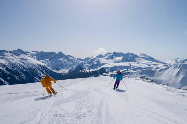 Couple skiing in the mountains Couple bonding through sport. Enjoying natures beauty as a couple. Skiing with friends. whistler skiing stock pictures, royalty-free photos & images