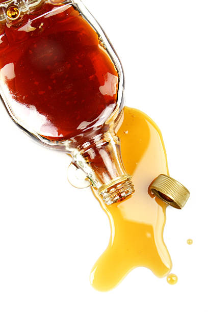 Spilled Syrup Maple syrup bottle spilled on a white background. maple syrup stock pictures, royalty-free photos & images