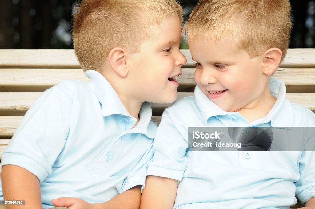 Due ragazzi Sussurrare segreti su una panca, esterno - Foto stock royalty-free di 2-3 anni