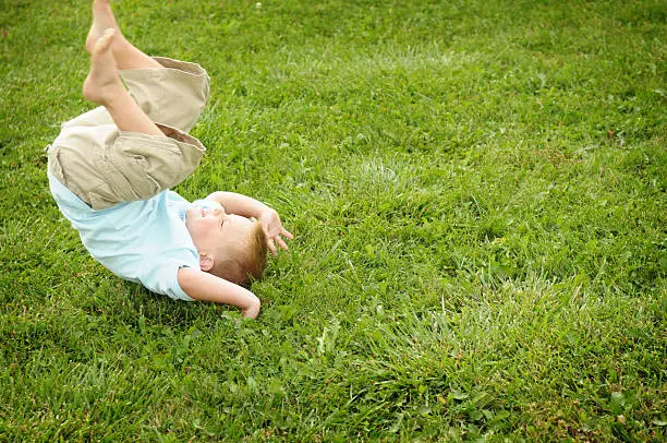 Little boy doing a somersault in the grass.