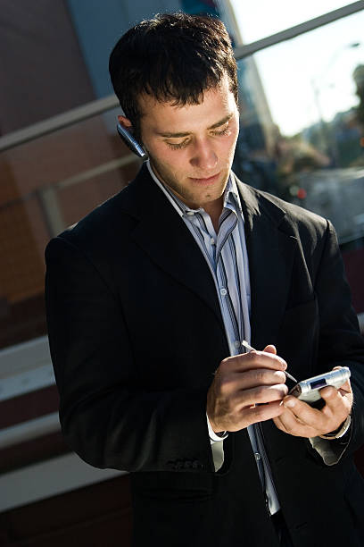 empresario en un teléfono celular con - hbgben100105 fotografías e imágenes de stock