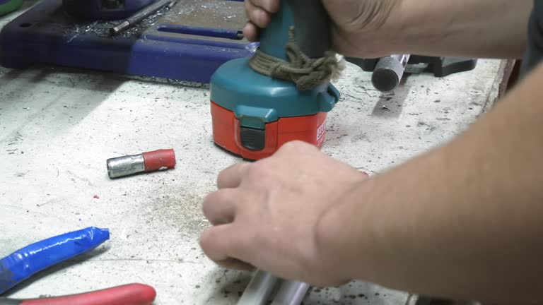 Drilling holes in a plastic rod with a hand drill. Working in your garage.