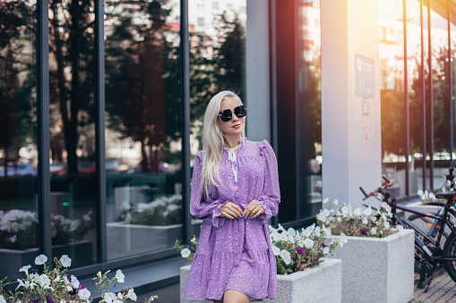 Young beautiful blonde hair woman in purple dress walking near business centre