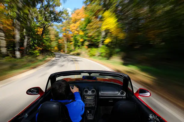Driving down a country road in a convertible sports car.