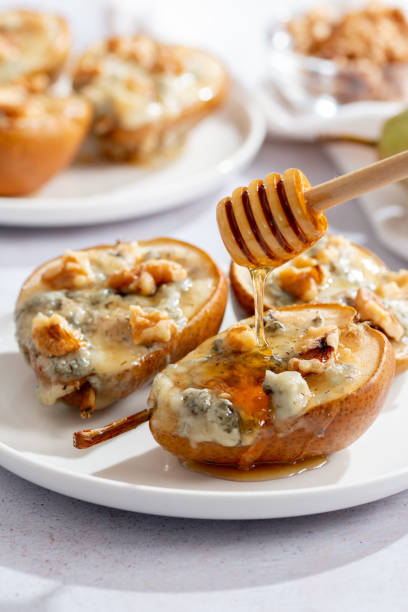 istock Baked pears with blue cheese, walnuts and honey on white plate and light background 1735726427