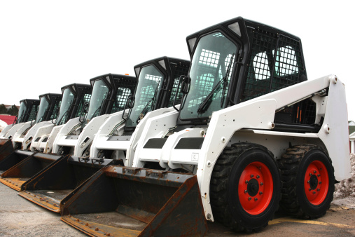A group of six multi purpose construction mini loaders ready to be used for sidewalk snow removal. Shot on a bright overcast day.