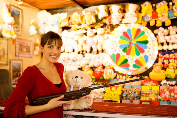 Little girl aiming at target with rifle during outdoors summer day vacations