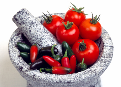 Tomatos and jalapeno peppers in a marble mortar with pestle. perfect set up for mexican salsa