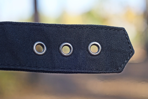 black harness made of fabric with metal rivets on the clothes in the street