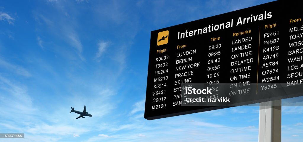 Tabla de llegadas y avión en el cielo - Foto de stock de Aeropuerto libre de derechos