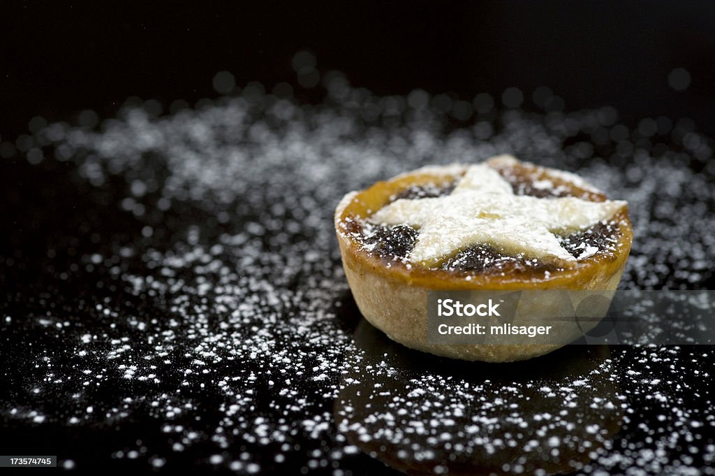 Single christmas mince pie on black background Festive mince pie with icing sugar on black background. Mince Pie Stock Photo