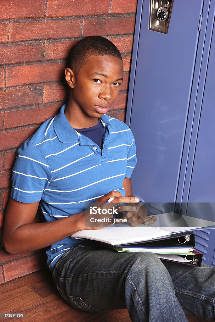 Teen at School A teenage boy sitting by his locker at school High School Student Stock Photo