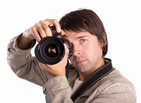 Professional photographer holding a professional camera in studio. About 25 years old, Caucasian male.