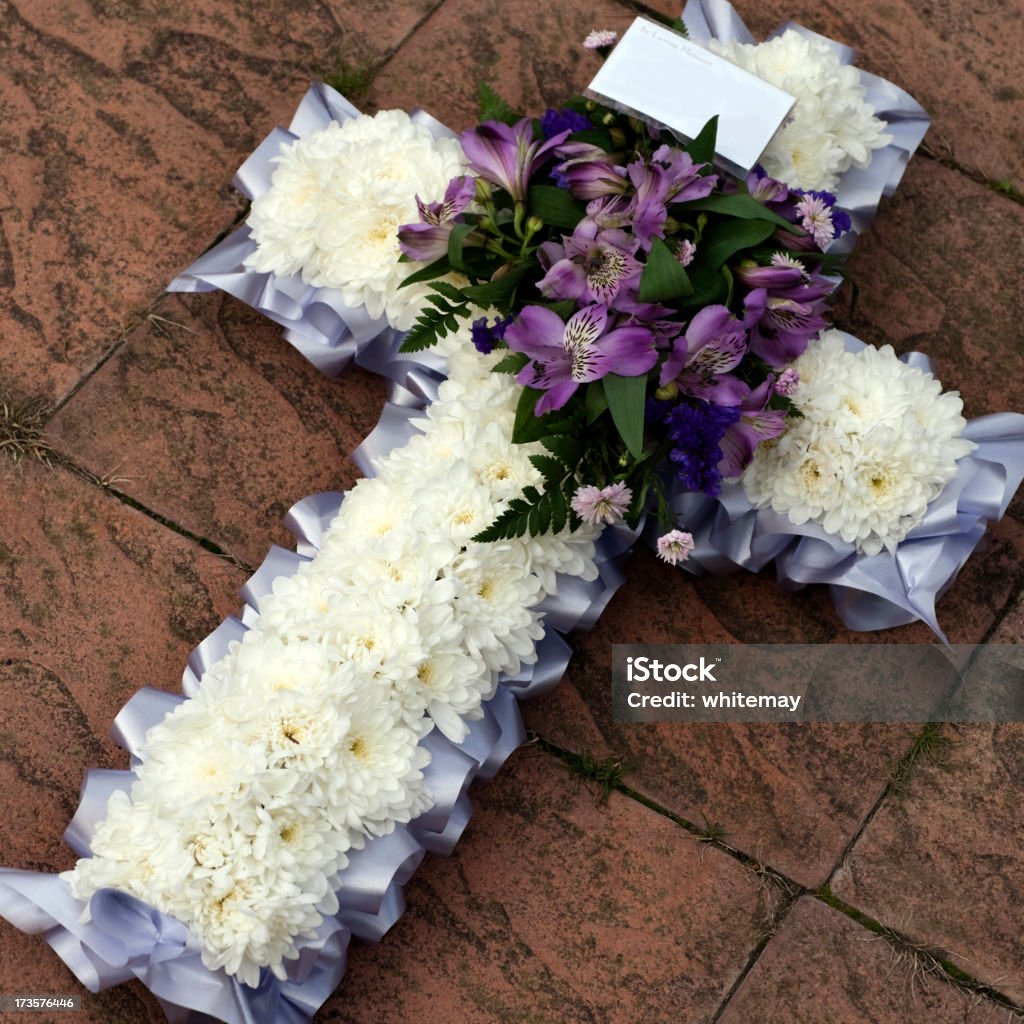 White and lilac cross Purple and lilac coloured flowers on a white daisy crucifix at a cemetery. With empty message tag.Also see: Cross Shape Stock Photo