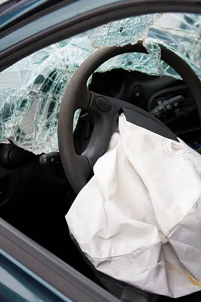 Photo of After affect of a car accident showing a deployed airbag