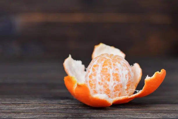 Peeled tangerine on wooden background with copy space