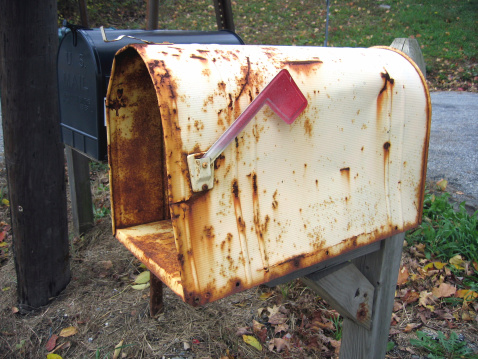Close-up of rustic white mailbox along countryside road.