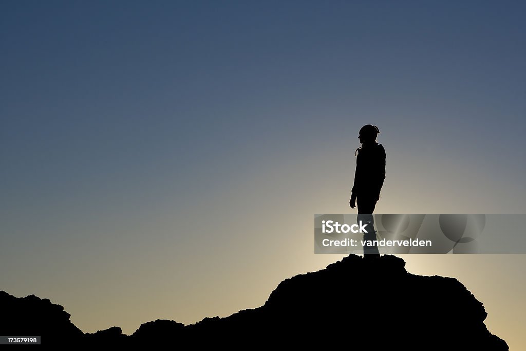 Silhouettes A hiker silhouetted against the sun at dusk on a rock. Achievement Stock Photo