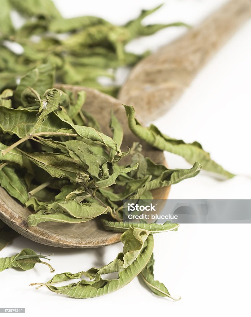 Lemon balm aka melissa "Dry melissa (lemon balm) leaves in an old wooden spoon.Selective focus, 60 mm, white background.The use of herbal remedies, including the herb melissa (balm, lemon balm), classified as Melissa officinalis, are popular as an alternative to standard Western allopathic medicine for a variety of problems, including an over-active thyroid, heart palpitations and depression as well as relaxing and reducing fevers." Alternative Medicine Stock Photo