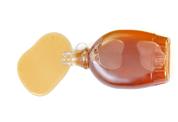 Spilled maple syrup Glass bottle with maple syrup isolated on white background maple syrup stock pictures, royalty-free photos & images