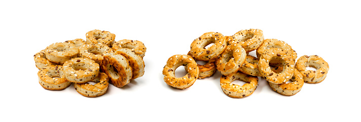 Taralli pile isolated. Small tarallini, crunchy bread rings, italian street food with herbs and seeds on white background