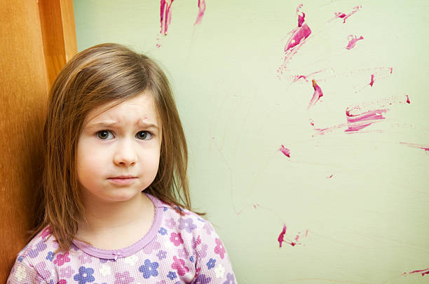 Worried Five-year-old girl ashamed and worried because she painted on the wall. sad girl crouching stock pictures, royalty-free photos & images