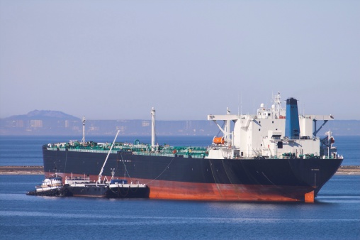 Large oil tanker in harbor for repairs and maintenance with tug and barge.  Victoria B.C in background