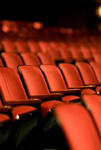 Rows and rows of Red theater seats.  Shallow depth of field. Vertical photograph.  Lots of room for copy.