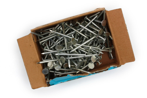 Box of aluminum roofing nails shot from above and the top of the box has been torn away. the cardboard box is isolated on a white background and the file comes with a clipping path. The shiny metal nails are stacked inside the box. - A great isolated object shot isolated on a white background.