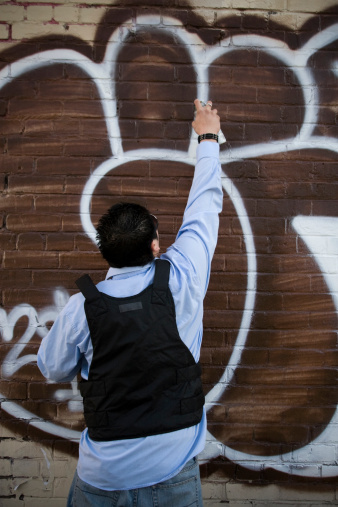 Young man tagging a wall with graffiti. Copy space above. CLICK FOR SIMILAR IMAGES AND LIGHTBOXes WITH MORE MEN OR ETHNIC FACES.