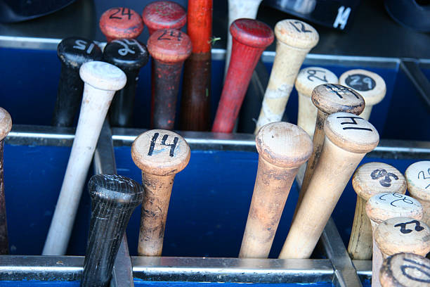 Baseball Bat Bin Bin full of bats with numbers on the bottom and helmets in the background baseball bat home run baseball wood stock pictures, royalty-free photos & images