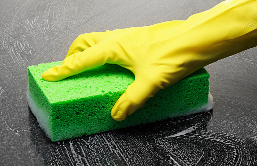 Cleaning a shiny surface with sponge and rubber gloves