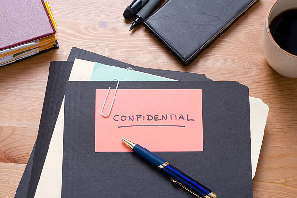 Black confidential files on a wooden desk with stationery stock photo
