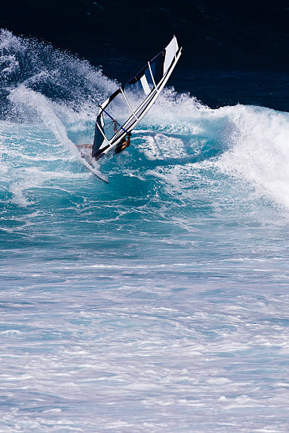 Windsurfer riding large waves in the ocean at Maui's north shore.